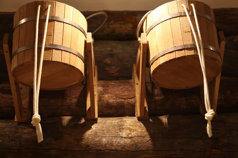 Cedar sauna buckets with rope handles against log walls at Private Banya Taiga