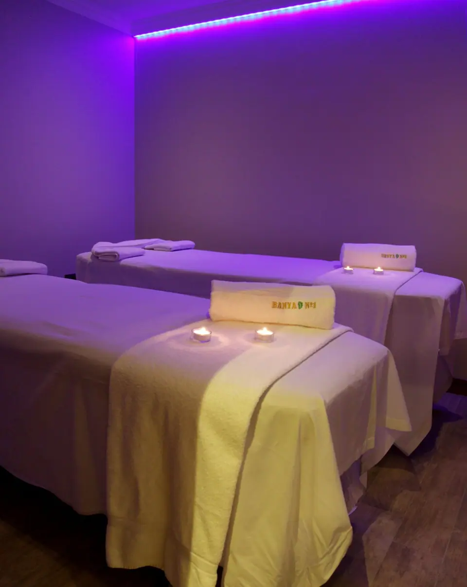 Treatment room with two massage beds and soft violet lighting