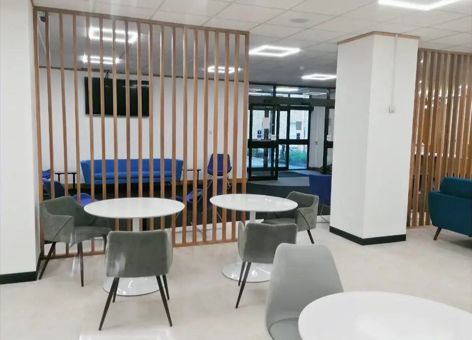 Office breakout area with round white tables, grey chairs and timber slatted screens