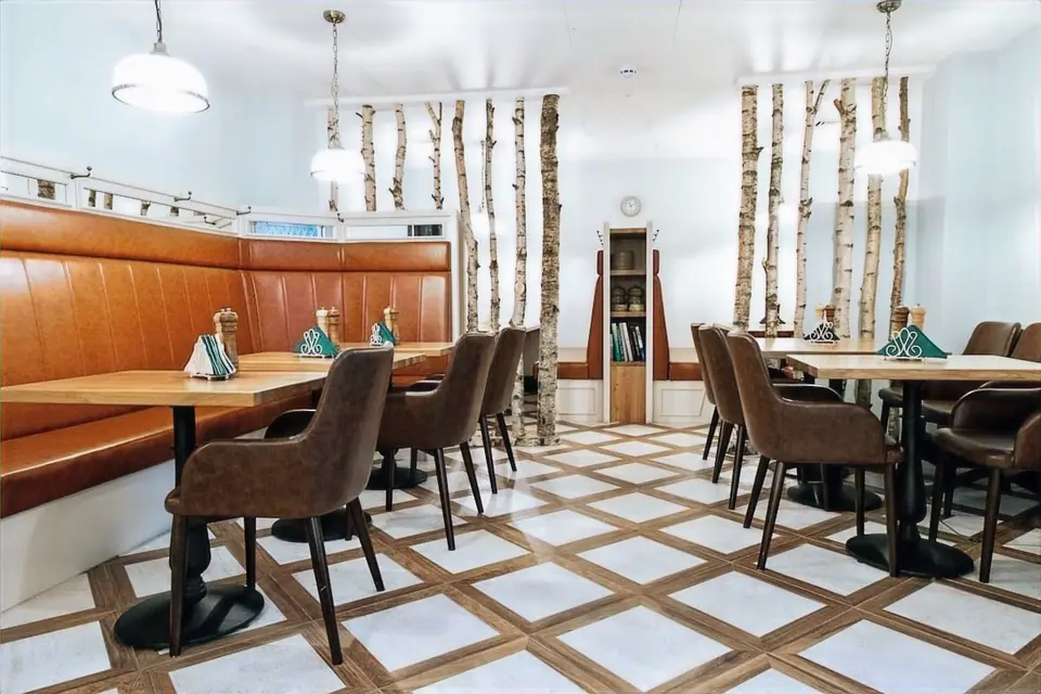 The Bath House café with tan leather banquettes, birch trunks and a diagonal parquet floor