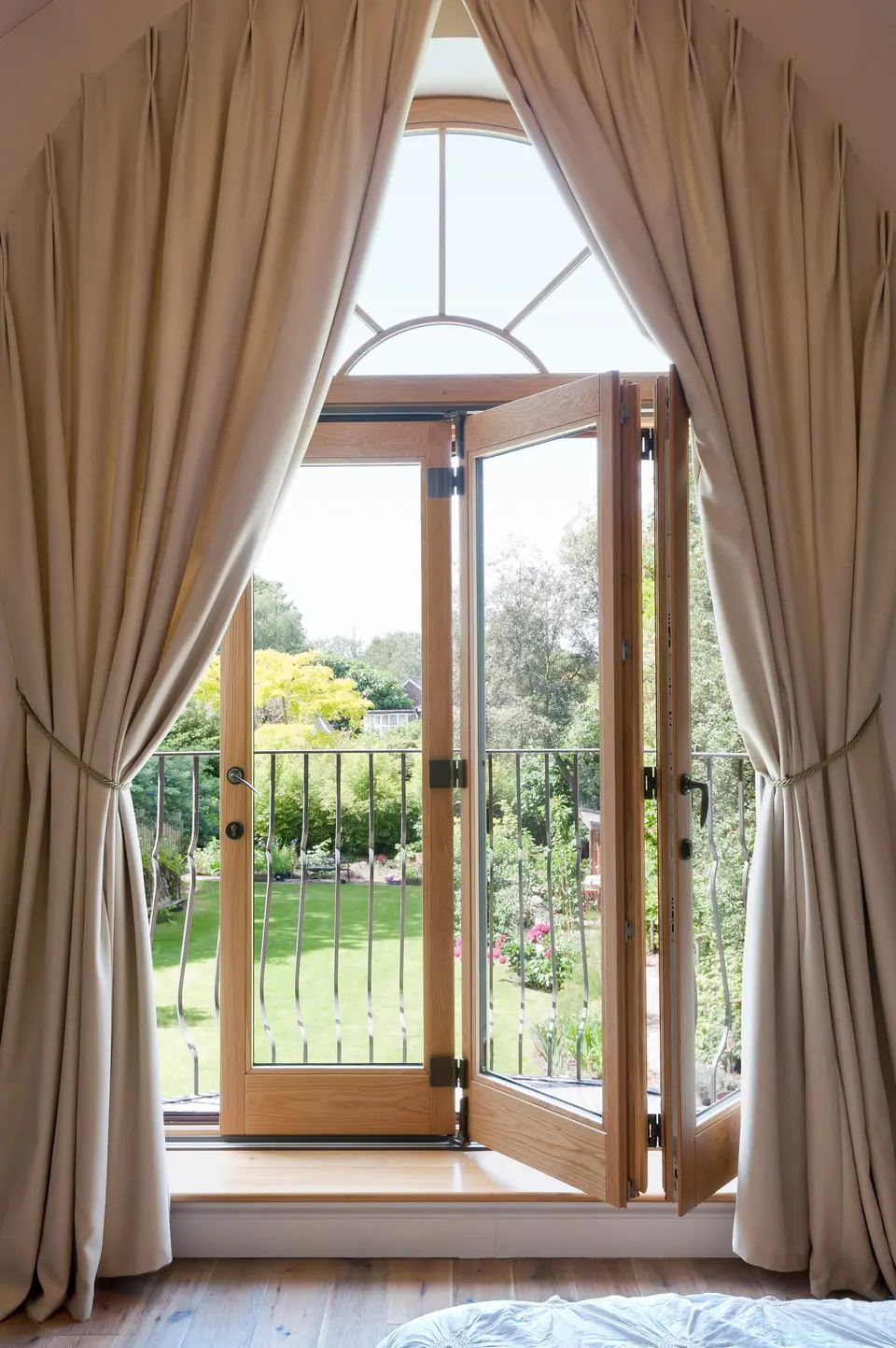 Arched timber French doors opening onto the garden, framed by full-length curtains