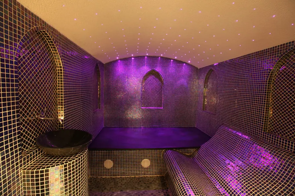 Vaulted mosaic steam room with violet lighting and a star-lit ceiling