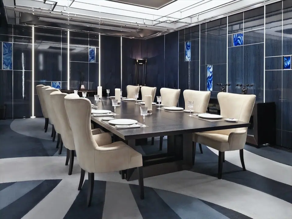 VIP dining room with a long dark table, cream upholstered chairs and a striped carpet