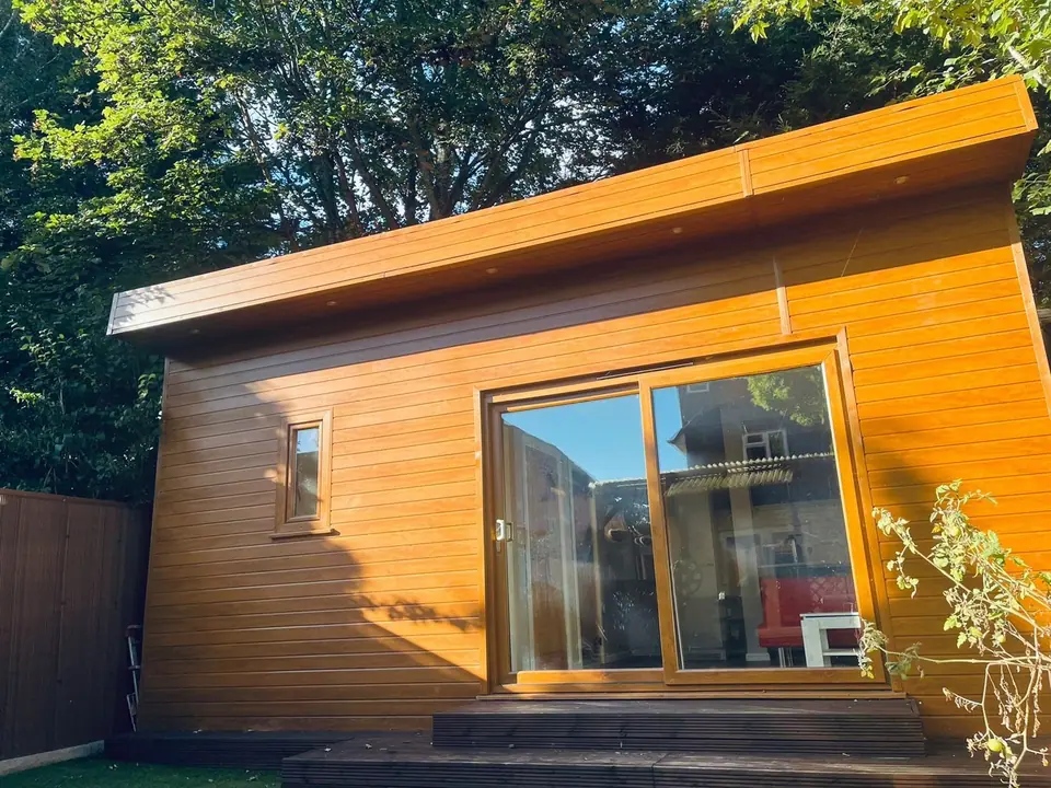 Timber-clad garden annex with sliding glass doors in afternoon sun