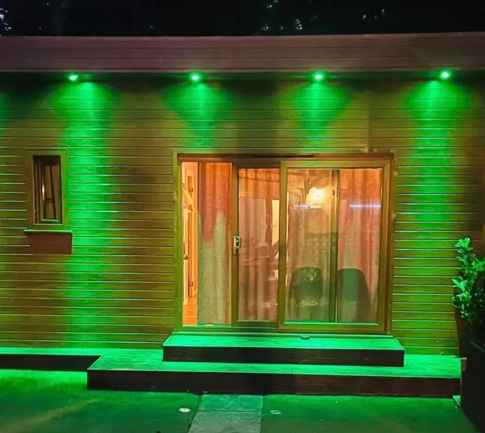 Garden annex at dusk with green uplighting and warm interior
