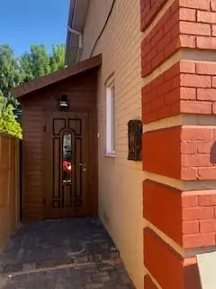 New timber porch with glazed door beside red brickwork