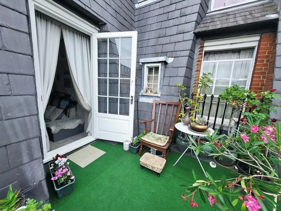 New white French door opening onto a planted roof terrace with slate walls