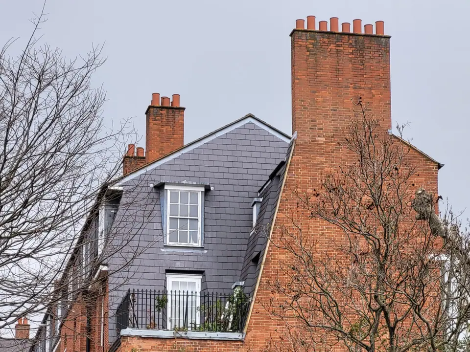 Red-brick Victorian mansion block with slate mansard roof and chimneys