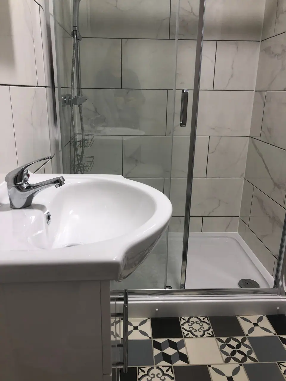 New shower room with white basin and monochrome patterned tiles