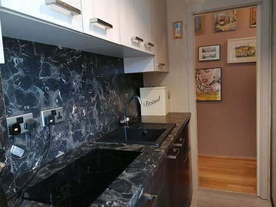 Black marble-effect worktop and splashback with an undermount sink