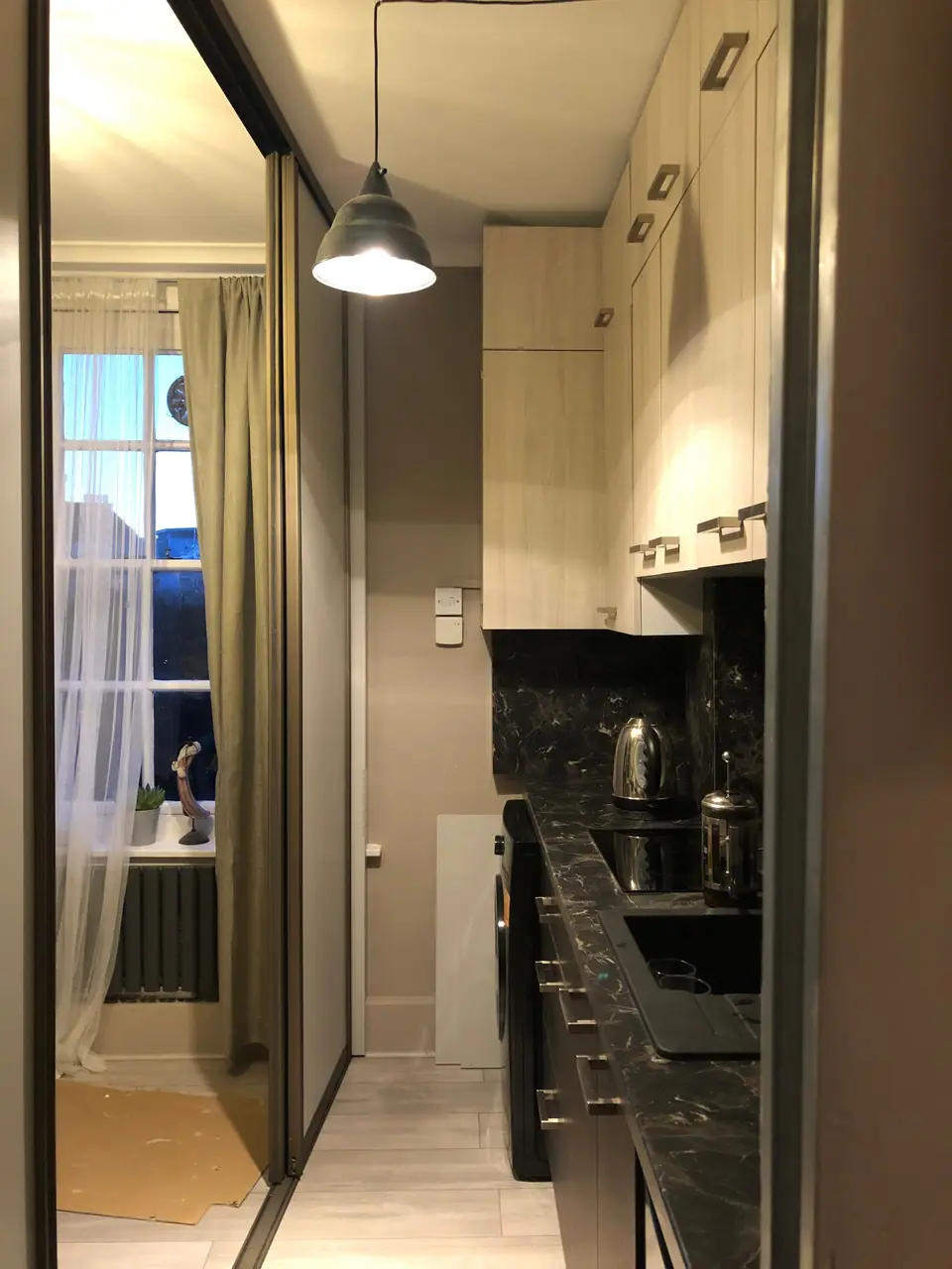 Narrow kitchen with mirrored sliding panels and a pendant light