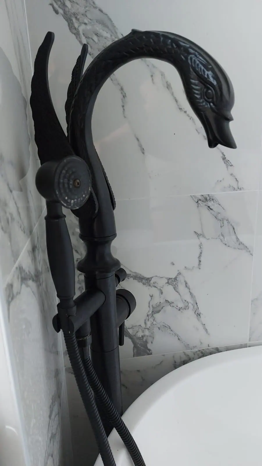 Black swan-neck bath mixer against marble-effect tiles