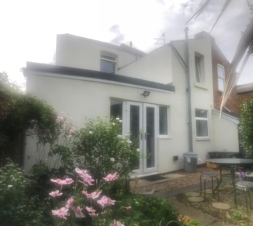 Completed white-rendered rear extension with French doors and a planted garden